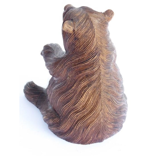 561 - A 19th century carved Black Forest bear; the corpulent animal seated and with outstretched paws (lef... 