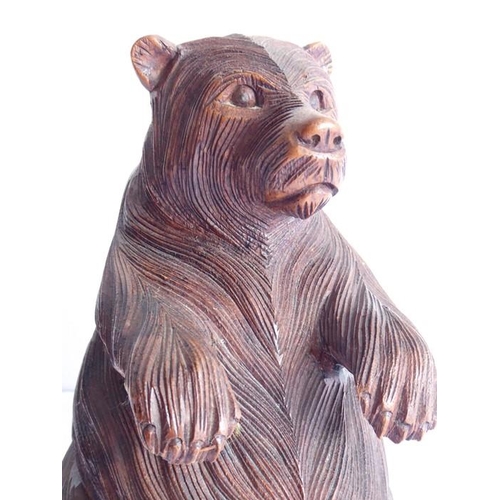 561 - A 19th century carved Black Forest bear; the corpulent animal seated and with outstretched paws (lef... 