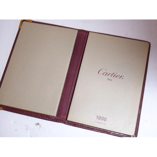 570 - Cartier of Paris, a ladies burgundy-leather clutch bag, together with a Cartier calendar notebook, a... 