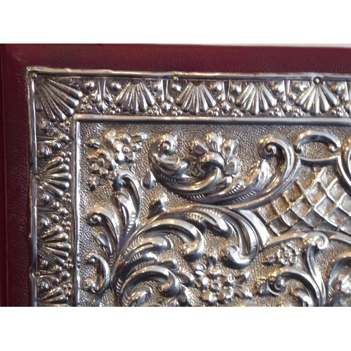 603 - A silver mounted desk blotter/paper pad; the highly ornate hallmarked silver front with vacant carto... 