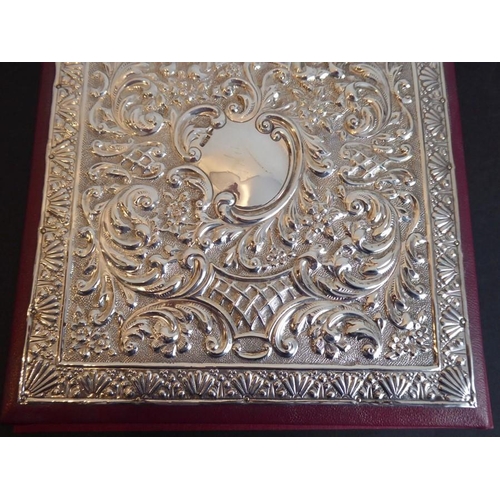 603 - A silver mounted desk blotter/paper pad; the highly ornate hallmarked silver front with vacant carto... 