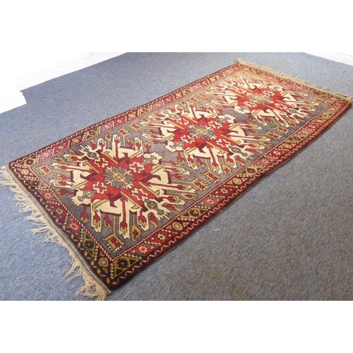 809 - A hand-knotted Turkish rug; three large red and cream ground spreading lozenges within borders with ... 