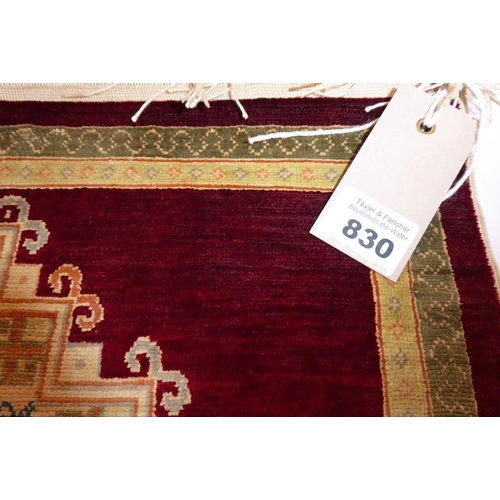 830 - A miniature signed Persian silkwork carpet; single central mustard-coloured lozenge against a red gr... 