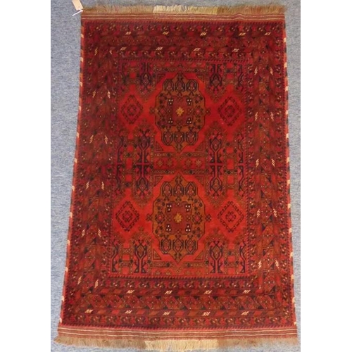 831 - A 20th century Afghan rug; predominately red ground with two central lozenges (150cm x 101cm)