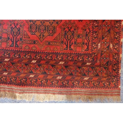 831 - A 20th century Afghan rug; predominately red ground with two central lozenges (150cm x 101cm)