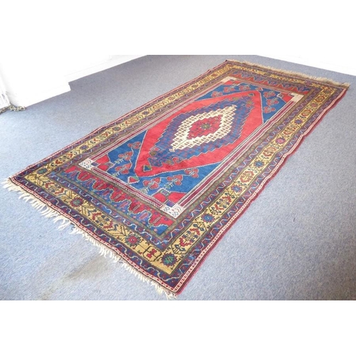 834 - A north-west Persia carpet; central lozenge with red, beige and dark-blue borders, and dark-blue spa... 