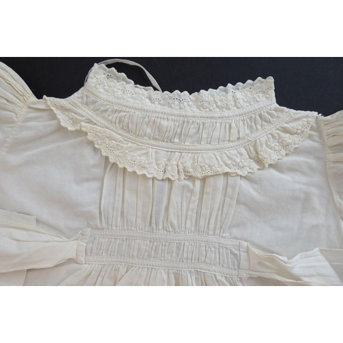 855 - A circa 1950s baby's nightgown; ivory-coloured cotton, gathered front with sash ties, long sleeves a... 