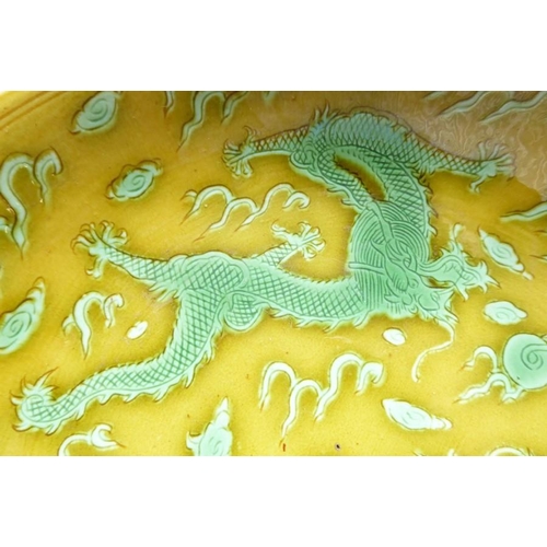 91 - A Chinese porcelain scrafitto dish; three green dragons chasing pearls amongst clouds against an oli... 