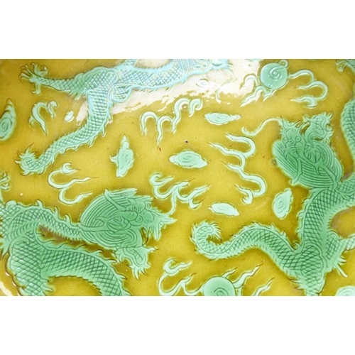 91 - A Chinese porcelain scrafitto dish; three green dragons chasing pearls amongst clouds against an oli... 