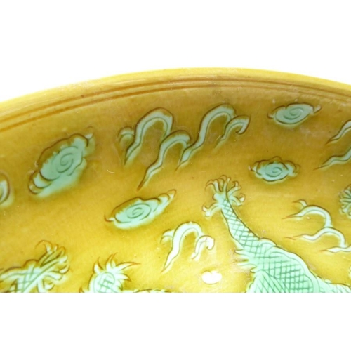 91 - A Chinese porcelain scrafitto dish; three green dragons chasing pearls amongst clouds against an oli... 