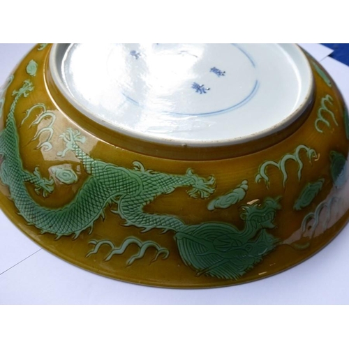 91 - A Chinese porcelain scrafitto dish; three green dragons chasing pearls amongst clouds against an oli... 