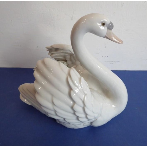27 - Four pieces of Lladro porcelain; a matched pair of swans (approx. 22cm high), another swan furling i... 