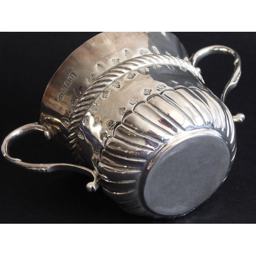 153 - A two-handled loving cup; in late 17th century style, elaborate cartouche with foliate repoussé deco... 