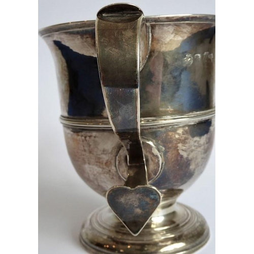 186 - A hallmarked silver two-handled loving cup; the handle terminals modelled as hearts, raised on sprea... 