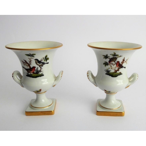 21 - A pair of Herend porcelain two-handled campana-style urns; hand gilded and decorated with differing ... 