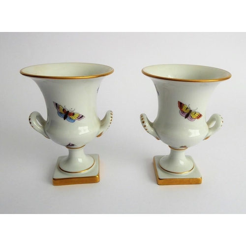 21 - A pair of Herend porcelain two-handled campana-style urns; hand gilded and decorated with differing ... 