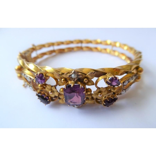 224 - An Edwardian amethyst, half pearl and 9 carat gold hinged bangle, the top section of the openwork te... 