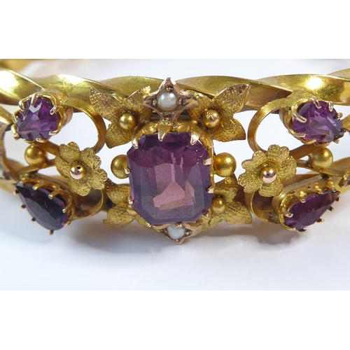 224 - An Edwardian amethyst, half pearl and 9 carat gold hinged bangle, the top section of the openwork te... 