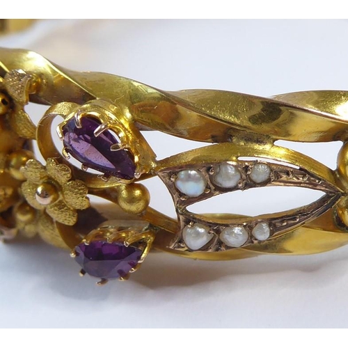 224 - An Edwardian amethyst, half pearl and 9 carat gold hinged bangle, the top section of the openwork te... 