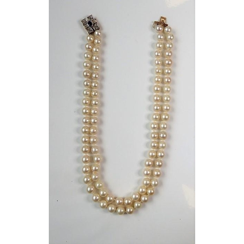 227 - A two-row cultured pearl necklace with gem-set clasp; the cultured pearls measuring 8mm in diameter,... 