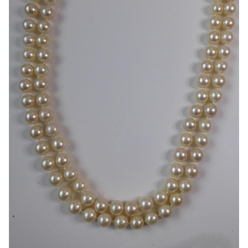 227 - A two-row cultured pearl necklace with gem-set clasp; the cultured pearls measuring 8mm in diameter,... 