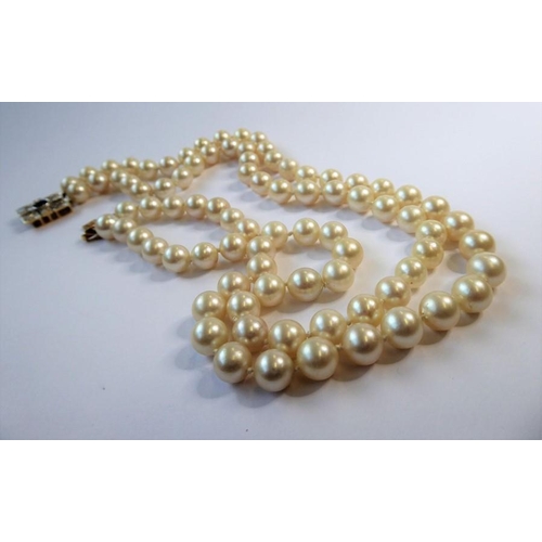 227 - A two-row cultured pearl necklace with gem-set clasp; the cultured pearls measuring 8mm in diameter,... 