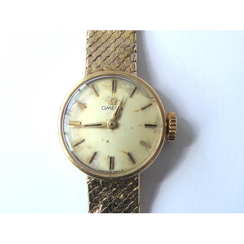 229 - A lady's 9-carat yellow-gold wristwatch by Omega; the champagne-coloured dial with baton markers sig... 