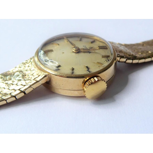 229 - A lady's 9-carat yellow-gold wristwatch by Omega; the champagne-coloured dial with baton markers sig... 