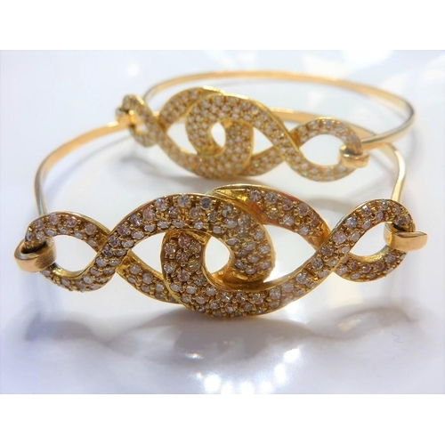 233 - A pair of diamond-set sprung bangles; each top section of entrelac brilliant-cut diamonds design, cl... 