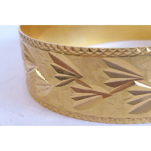 234 - A bangle, decorated with foliate and matt engraving, foreign control mark, (with insurance valuation... 