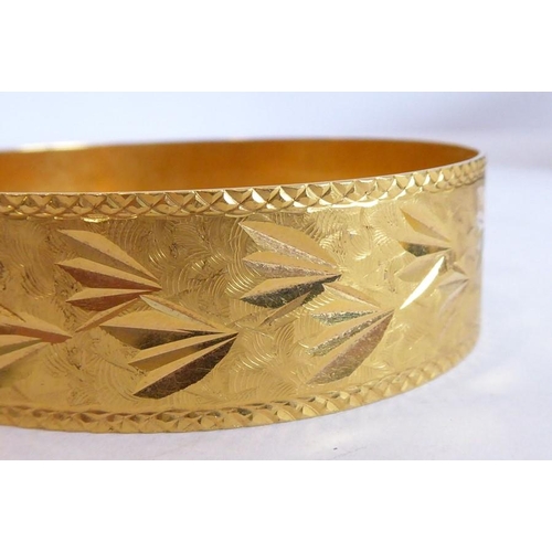 234 - A bangle, decorated with foliate and matt engraving, foreign control mark, (with insurance valuation... 