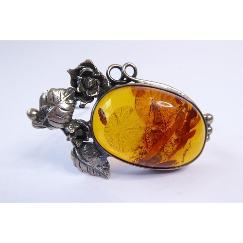 238 - Two amber bead and 'nugget' necklaces, one further and an oval amber brooch within a scrolling surro... 