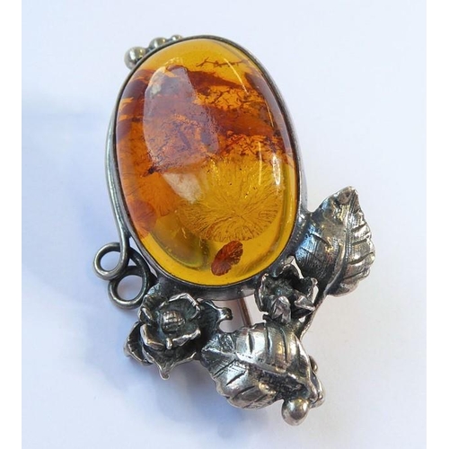 238 - Two amber bead and 'nugget' necklaces, one further and an oval amber brooch within a scrolling surro... 