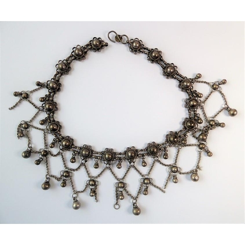 240 - An Indian-inspired fringe necklace, the flowerhead clusters suspending an ornate graduated chain and... 