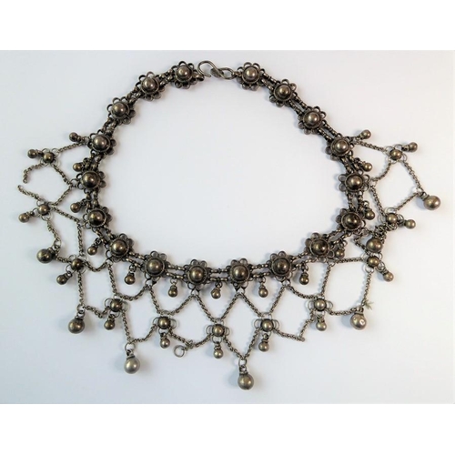 240 - An Indian-inspired fringe necklace, the flowerhead clusters suspending an ornate graduated chain and... 