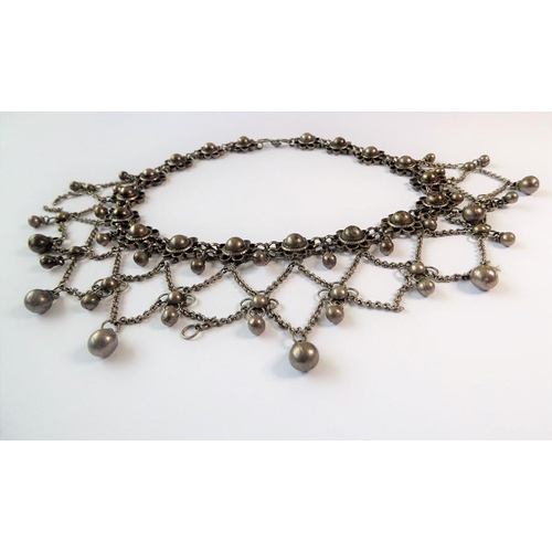 240 - An Indian-inspired fringe necklace, the flowerhead clusters suspending an ornate graduated chain and... 