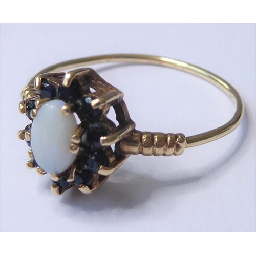 243 - A cabochon opal and sapphire-set cluster ring to the 9 carat yellow gold ornate shoulders and wirewo... 