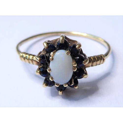 243 - A cabochon opal and sapphire-set cluster ring to the 9 carat yellow gold ornate shoulders and wirewo... 