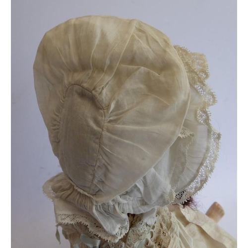 326 - An early 20th century bisque-headed doll in cream lacework gown and bonnet; composition body (damage... 