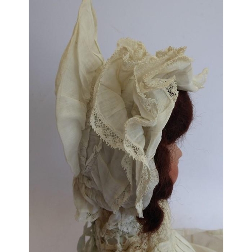 326 - An early 20th century bisque-headed doll in cream lacework gown and bonnet; composition body (damage... 