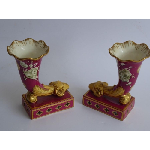 35 - A pair of 19th century hand gilded and decorated porcelain cornucopia; ram's head terminals above re... 