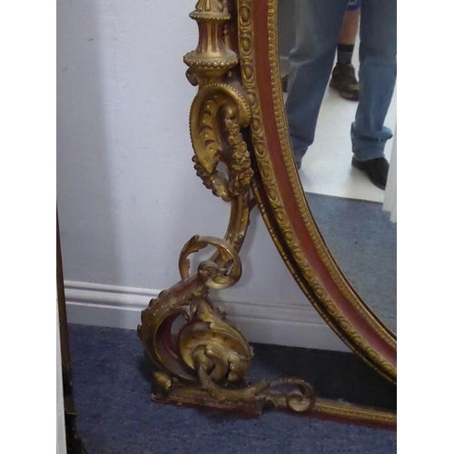 649 - A very large 19th century parcel gilt and rust-coloured painted overmantle looking glass of oval for... 