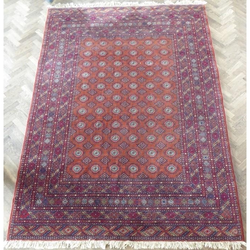 710 - A machine made orange and red ground Turkman carpet in good condition (287cm x 200cm)