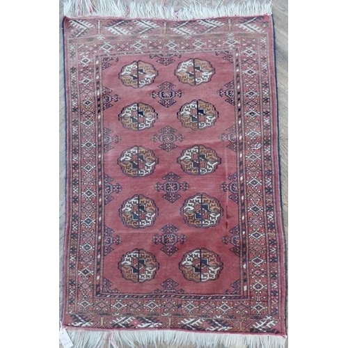 728 - A small red ground Afghan rug with gul pattern (124cm x 85cm)