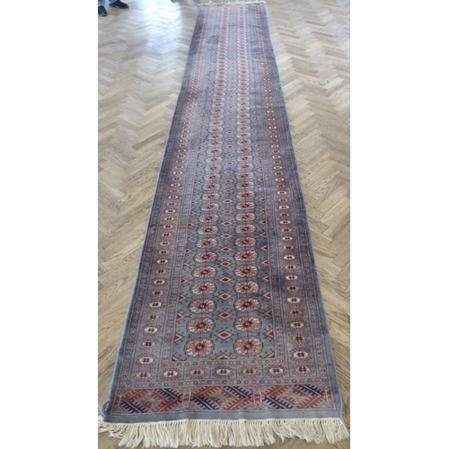 730 - A light-blue ground Pakistan runner with gul pattern (480cm x 79cm)