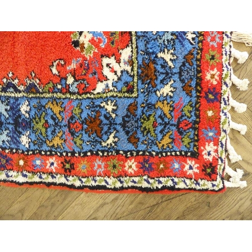 746 - A Moroccan Rabat carpet; central flowerheads against a red ground within blue and red varying sized ... 