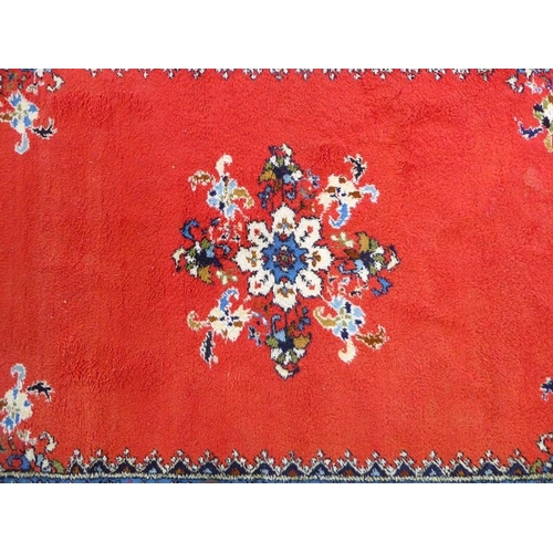 746 - A Moroccan Rabat carpet; central flowerheads against a red ground within blue and red varying sized ... 