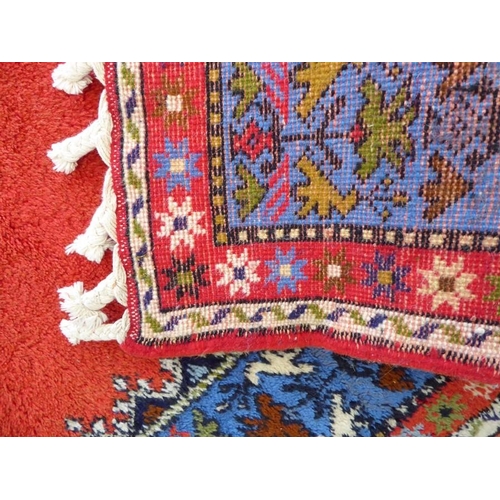 746 - A Moroccan Rabat carpet; central flowerheads against a red ground within blue and red varying sized ... 