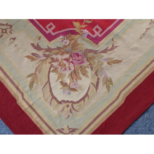 753 - An Aubusson wall-hanging tapestry with a central floral motif and crimson border decorated with vari... 