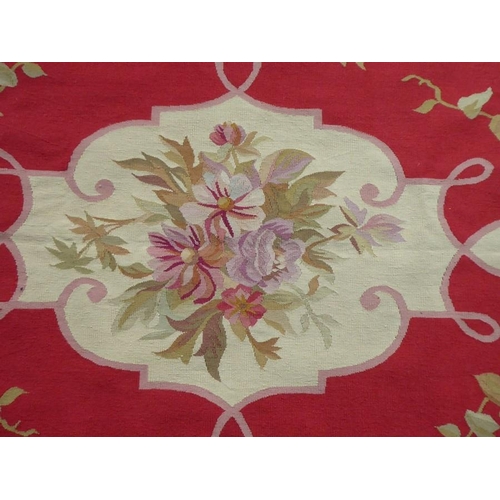 753 - An Aubusson wall-hanging tapestry with a central floral motif and crimson border decorated with vari... 